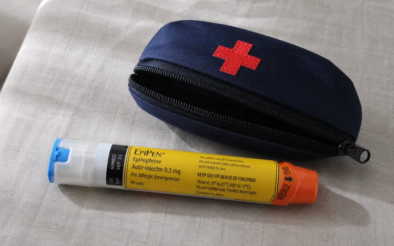 Epinephrine auto-injector resting beside a compact first-aid pouch on a white surface